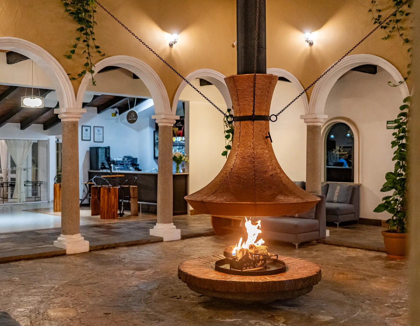 Patio de arcos con la chimenea de cobre encendida al anochecer