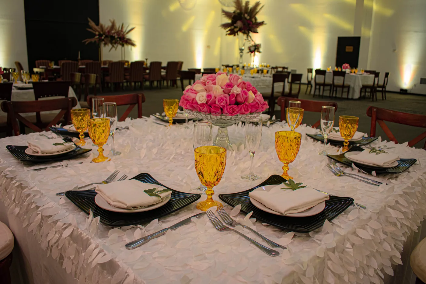 Salón de eventos montado con mesas vestidas e iluminación cálida