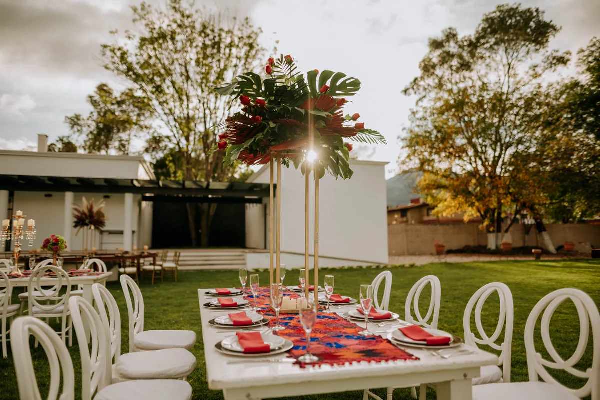 Mesa con centro floral tropical alto en el jardín al atardecer