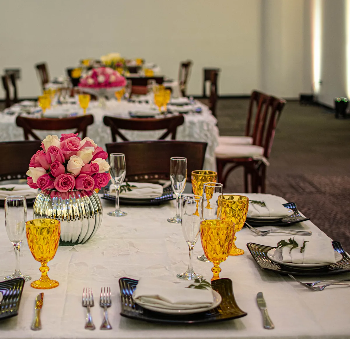 Detalle de mesa montada en el salón con cristalería ámbar y flores