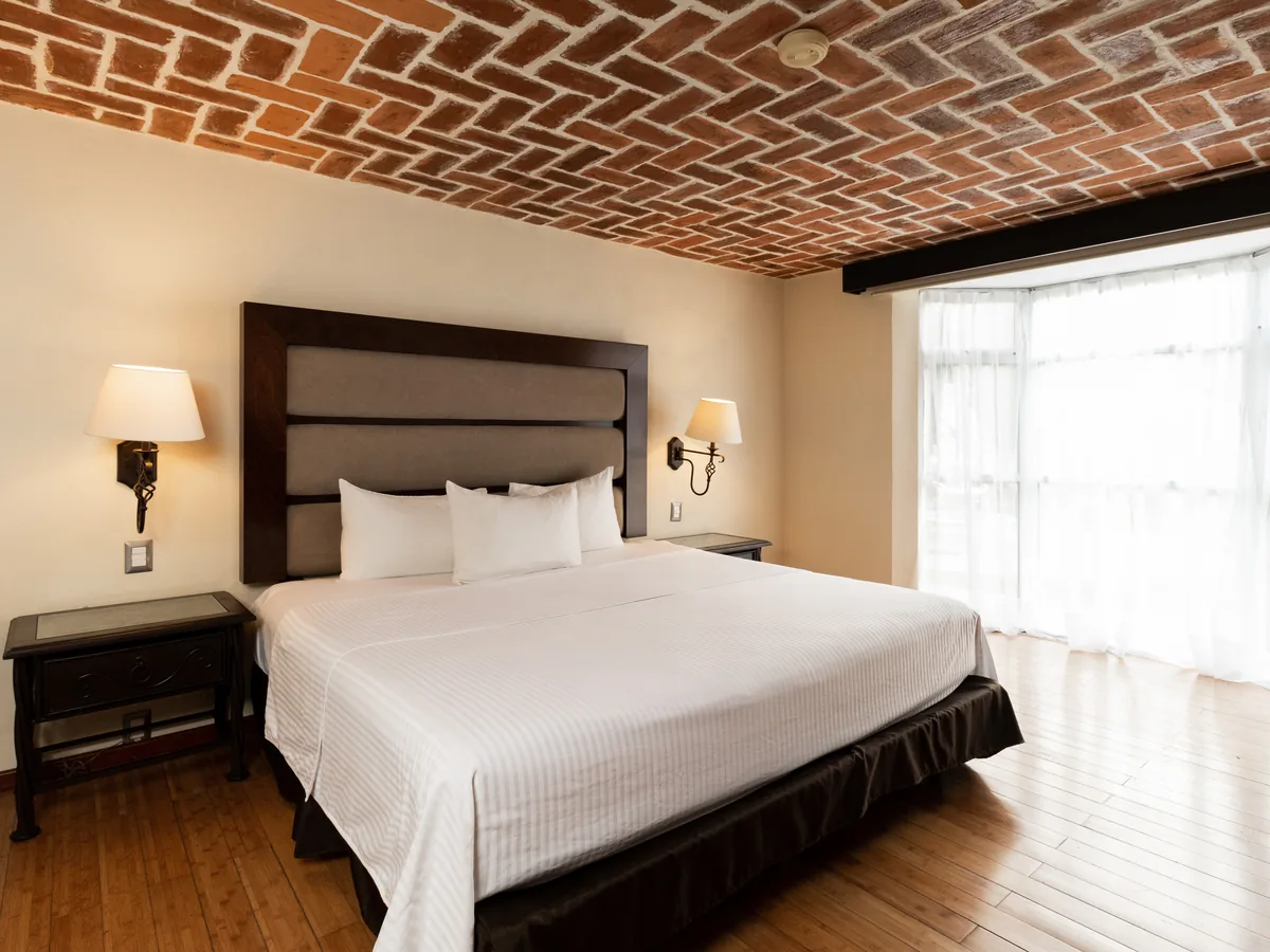 Habitación de Lujo con cama king bajo la bóveda de ladrillo y luz del ventanal