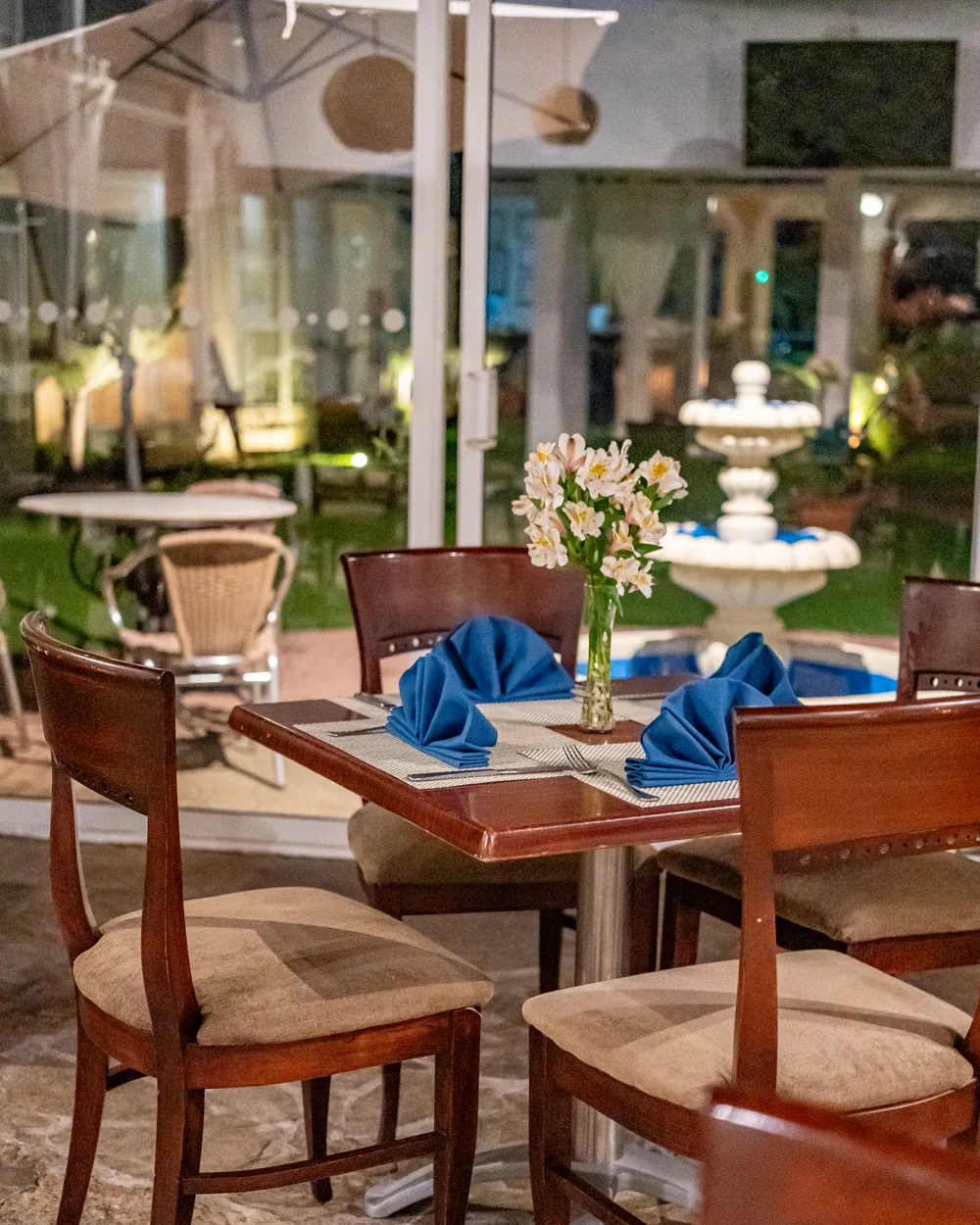 Mesa junto al ventanal, con la fuente del jardín iluminada al otro lado del cristal